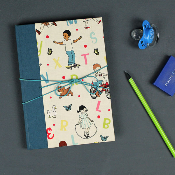 Cremefarbenes Babytagebuch im Retrolook mit spielenden Kindern