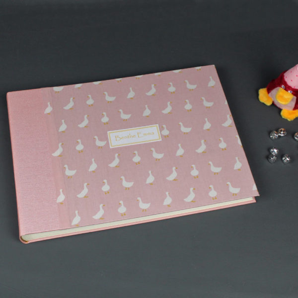 Rosa Babyfotoalbum mit kleinen weißen Gänsen